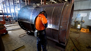 Person working on a large metal pipe in factory